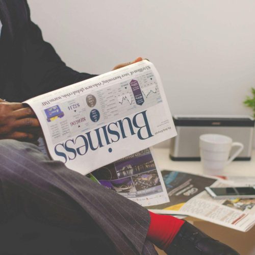 Businessman reading a financial newspaper at a desk, highlighting finance and commerce theme.